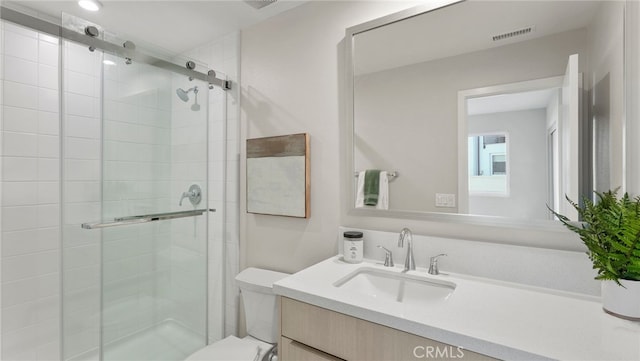 bathroom with vanity, a shower with shower door, and toilet