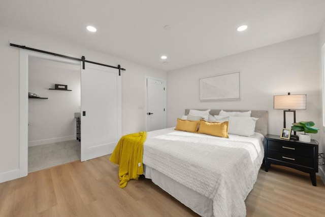 bedroom featuring a barn door and light wood-type flooring