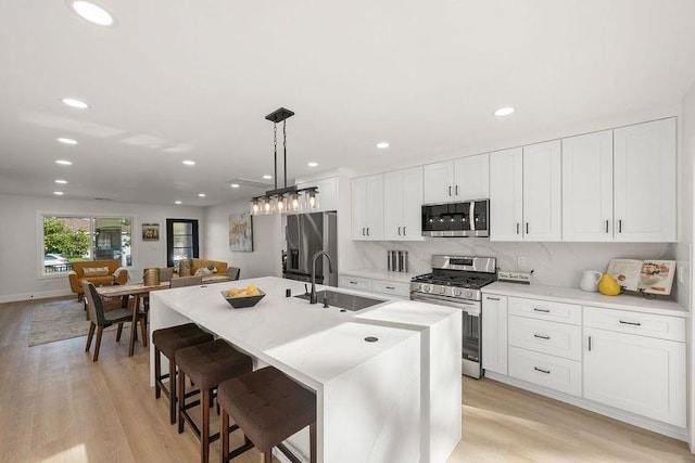 kitchen with appliances with stainless steel finishes, sink, a center island with sink, and white cabinets