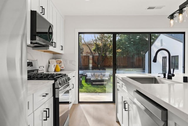 kitchen featuring tasteful backsplash, sink, white cabinets, and appliances with stainless steel finishes