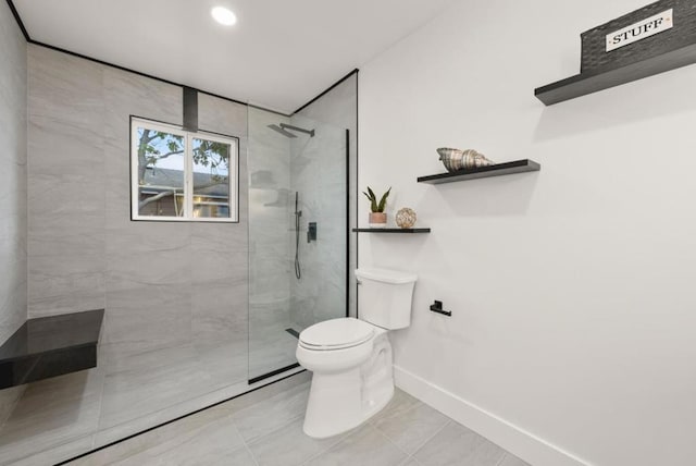 bathroom with tile patterned flooring, tiled shower, and toilet