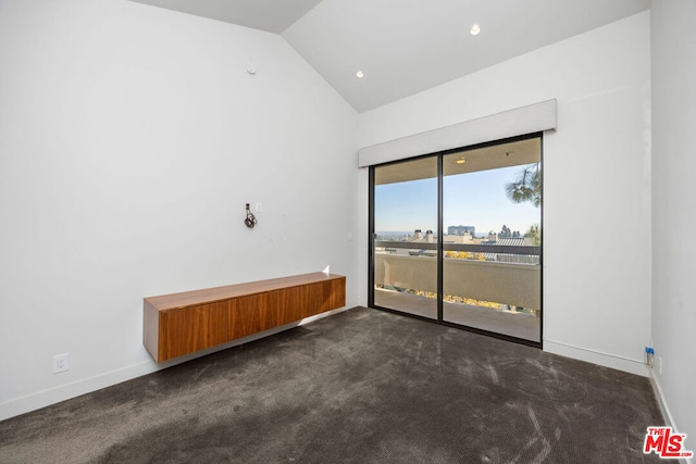 unfurnished room featuring lofted ceiling and dark carpet