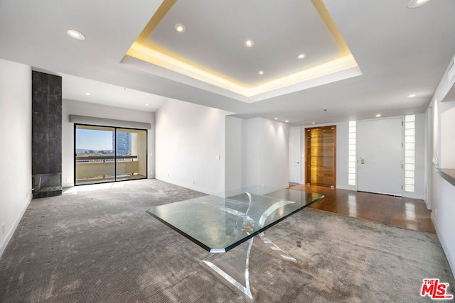 unfurnished living room featuring a tray ceiling and carpet