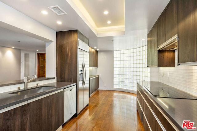 kitchen featuring hardwood / wood-style floors, sink, backsplash, stainless steel appliances, and dark brown cabinets