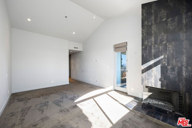 unfurnished living room featuring high vaulted ceiling and carpet