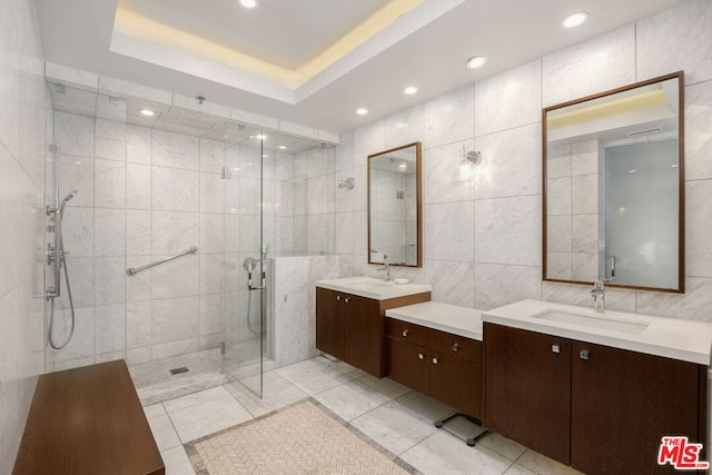 bathroom featuring a shower with door, vanity, tile walls, and a tray ceiling