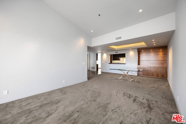 unfurnished living room with carpet and a tray ceiling