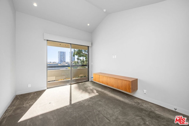 unfurnished room featuring vaulted ceiling and dark colored carpet