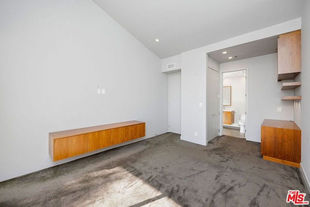 interior space featuring vaulted ceiling and dark carpet