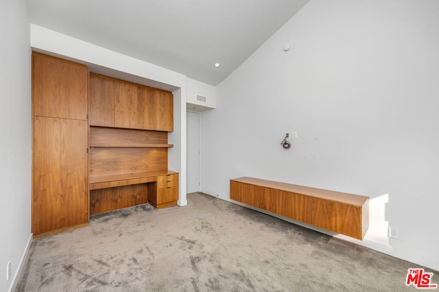 unfurnished living room featuring light carpet and vaulted ceiling