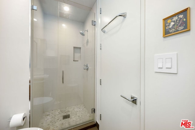 bathroom with a shower with door and toilet