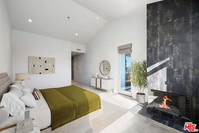 bedroom featuring a large fireplace and high vaulted ceiling