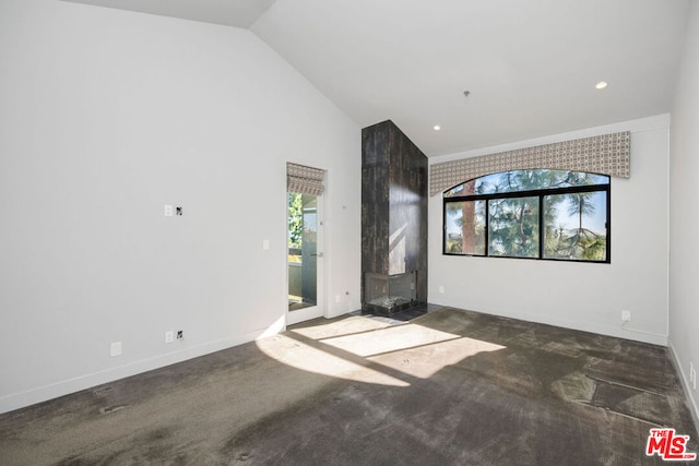 carpeted spare room featuring high vaulted ceiling