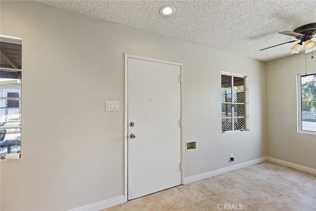 foyer with ceiling fan, light tile patterned floors, and a textured ceiling