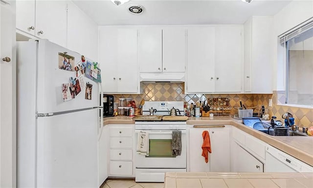 kitchen featuring white cabinetry, backsplash, tile counters, light tile patterned floors, and white appliances