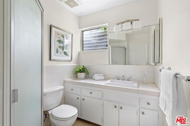 bathroom with vanity, toilet, an enclosed shower, and tile walls