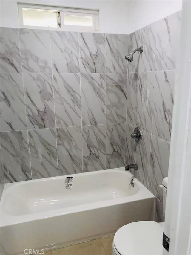 bathroom featuring toilet, tiled shower / bath combo, and a healthy amount of sunlight