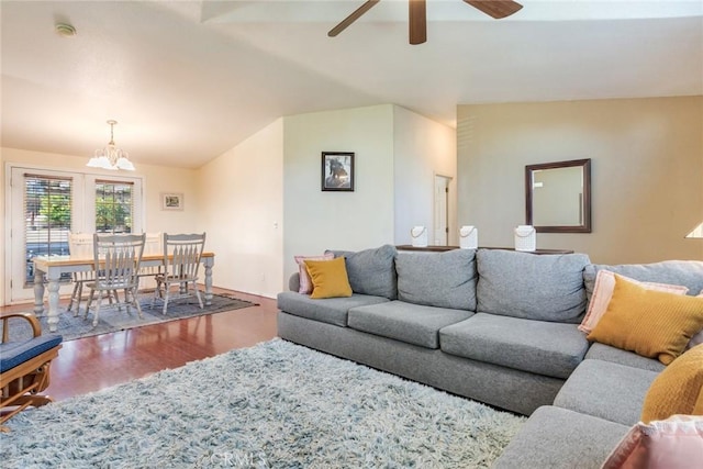 living room featuring lofted ceiling, ceiling fan with notable chandelier, and wood-type flooring