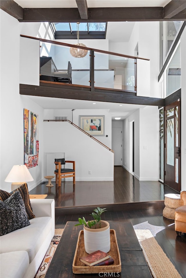 living room with a towering ceiling, dark hardwood / wood-style floors, and beam ceiling