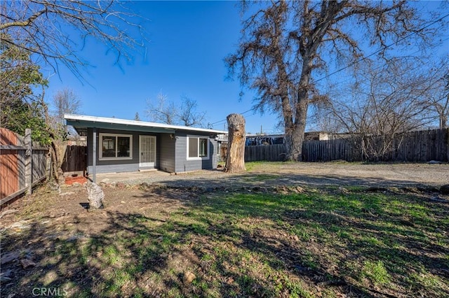 back of house with a fenced backyard and a lawn