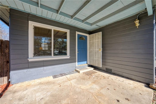 view of exterior entry featuring crawl space, a patio area, and fence