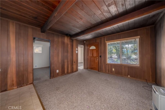 empty room with wooden ceiling, light colored carpet, beam ceiling, and wooden walls