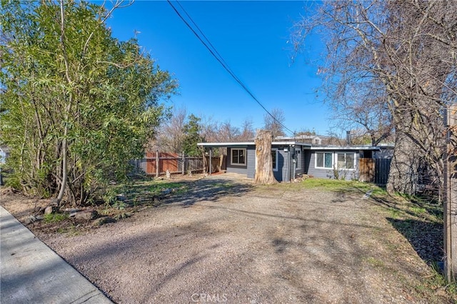 view of front of home with fence and dirt driveway