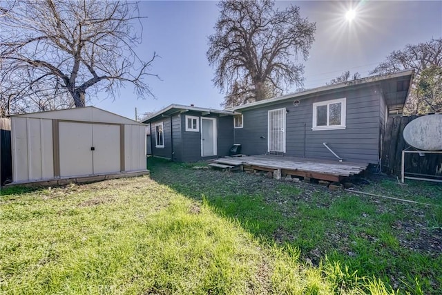 rear view of property with an outbuilding, a lawn, fence, a shed, and a wooden deck