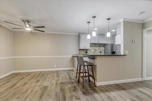 kitchen with a breakfast bar, hanging light fixtures, stainless steel refrigerator with ice dispenser, white cabinets, and kitchen peninsula