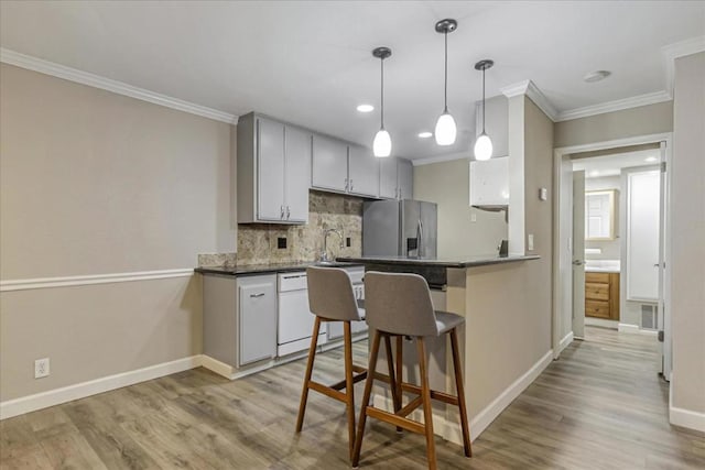 kitchen with light hardwood / wood-style flooring, stainless steel refrigerator with ice dispenser, tasteful backsplash, ornamental molding, and kitchen peninsula