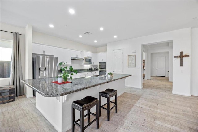 kitchen featuring dark stone countertops, a spacious island, white cabinets, and appliances with stainless steel finishes