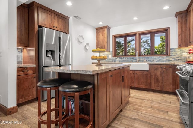 kitchen featuring decorative backsplash, a breakfast bar, a center island, and appliances with stainless steel finishes