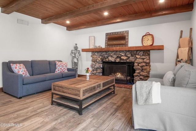 living room with hardwood / wood-style flooring, a stone fireplace, wood ceiling, and beamed ceiling