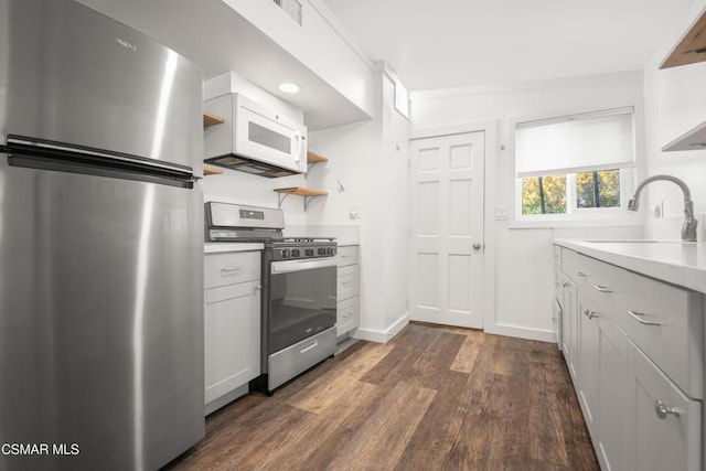 kitchen with sink, dark wood-type flooring, stainless steel appliances, and white cabinets