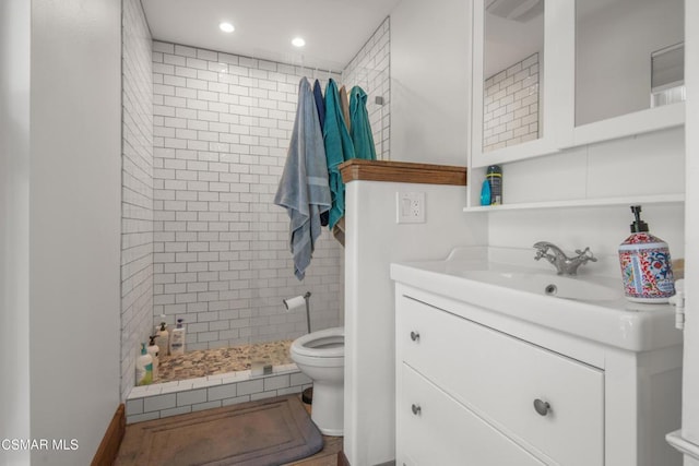 bathroom featuring vanity, tiled shower, and toilet