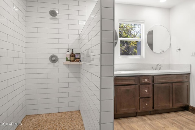 bathroom featuring hardwood / wood-style flooring, vanity, and a tile shower