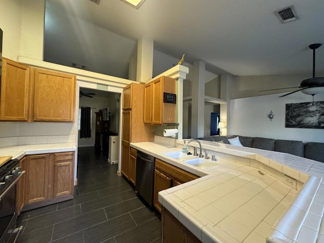 kitchen featuring stainless steel gas stove, tile counters, black dishwasher, and vaulted ceiling