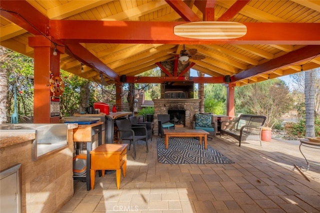 view of patio featuring a gazebo, ceiling fan, and an outdoor living space with a fireplace