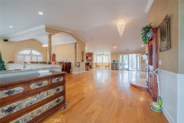 hall with crown molding, light wood-type flooring, and ornate columns