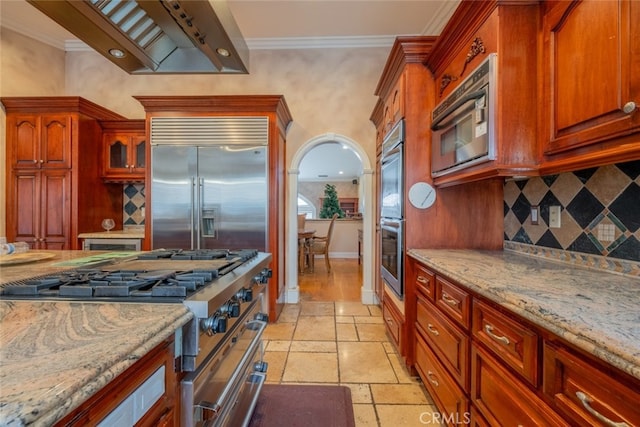 kitchen featuring tasteful backsplash, premium appliances, light stone counters, and ornamental molding