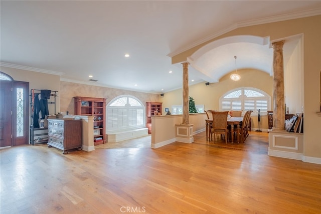 interior space featuring lofted ceiling, crown molding, decorative columns, and light wood-type flooring