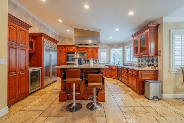 kitchen featuring wine cooler, a breakfast bar, ornamental molding, an island with sink, and stainless steel appliances