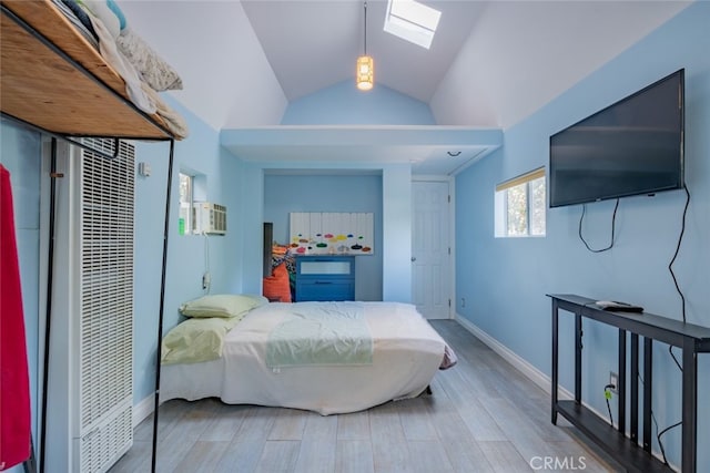 bedroom featuring hardwood / wood-style flooring, a wall unit AC, and vaulted ceiling with skylight