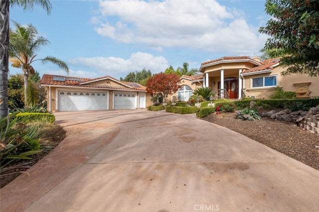 mediterranean / spanish-style house with a garage and solar panels