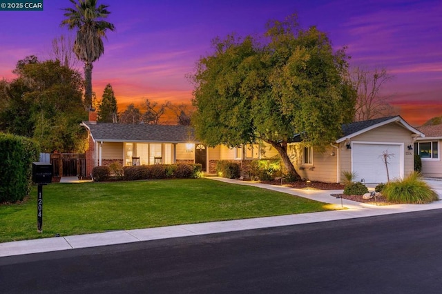 ranch-style house featuring a garage and a lawn