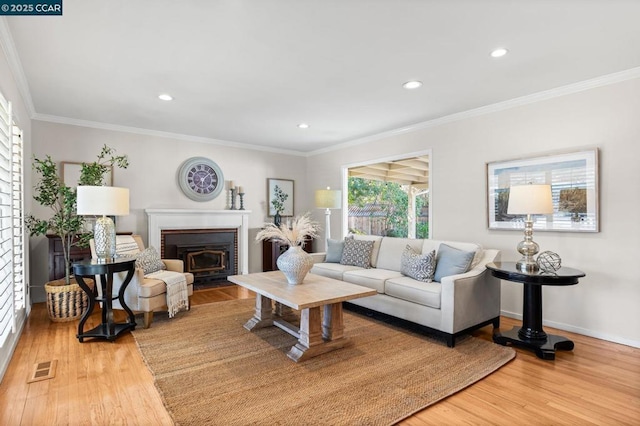 living room with crown molding, a fireplace, and light hardwood / wood-style flooring