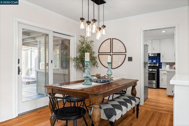 dining room with crown molding, light hardwood / wood-style flooring, and a chandelier