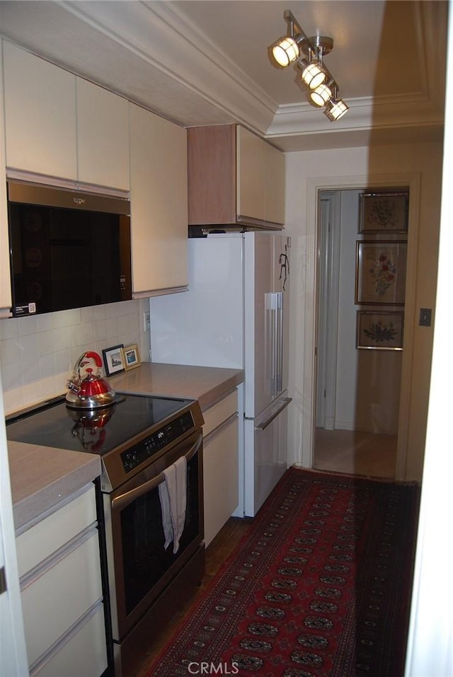 kitchen with backsplash, crown molding, stainless steel range with electric cooktop, and white refrigerator