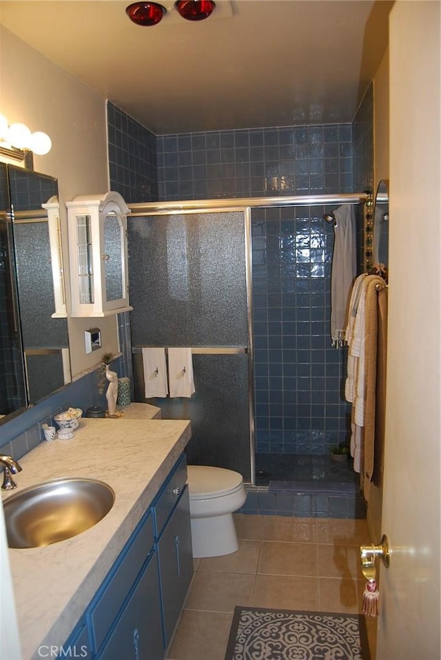 bathroom featuring an enclosed shower, vanity, tile patterned floors, and toilet