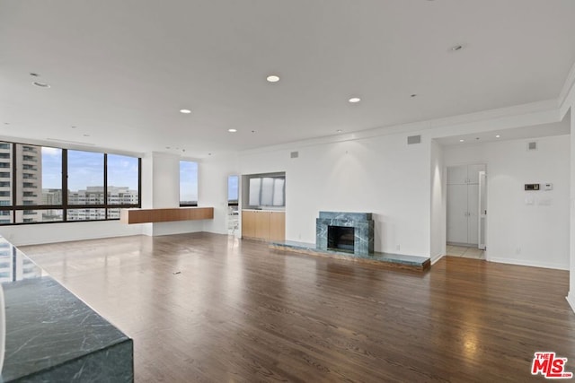 unfurnished living room featuring crown molding, a premium fireplace, and dark hardwood / wood-style flooring